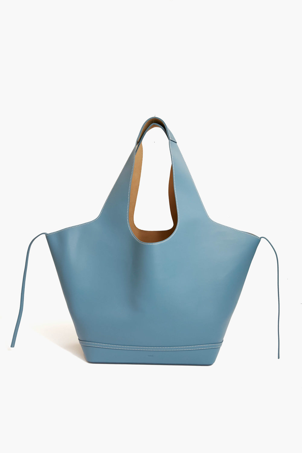 The Vasic Aqua Mask Tote is a large, light blue leather tote bag featuring a cut-out handle and extended side panels—perfect for everyday use.