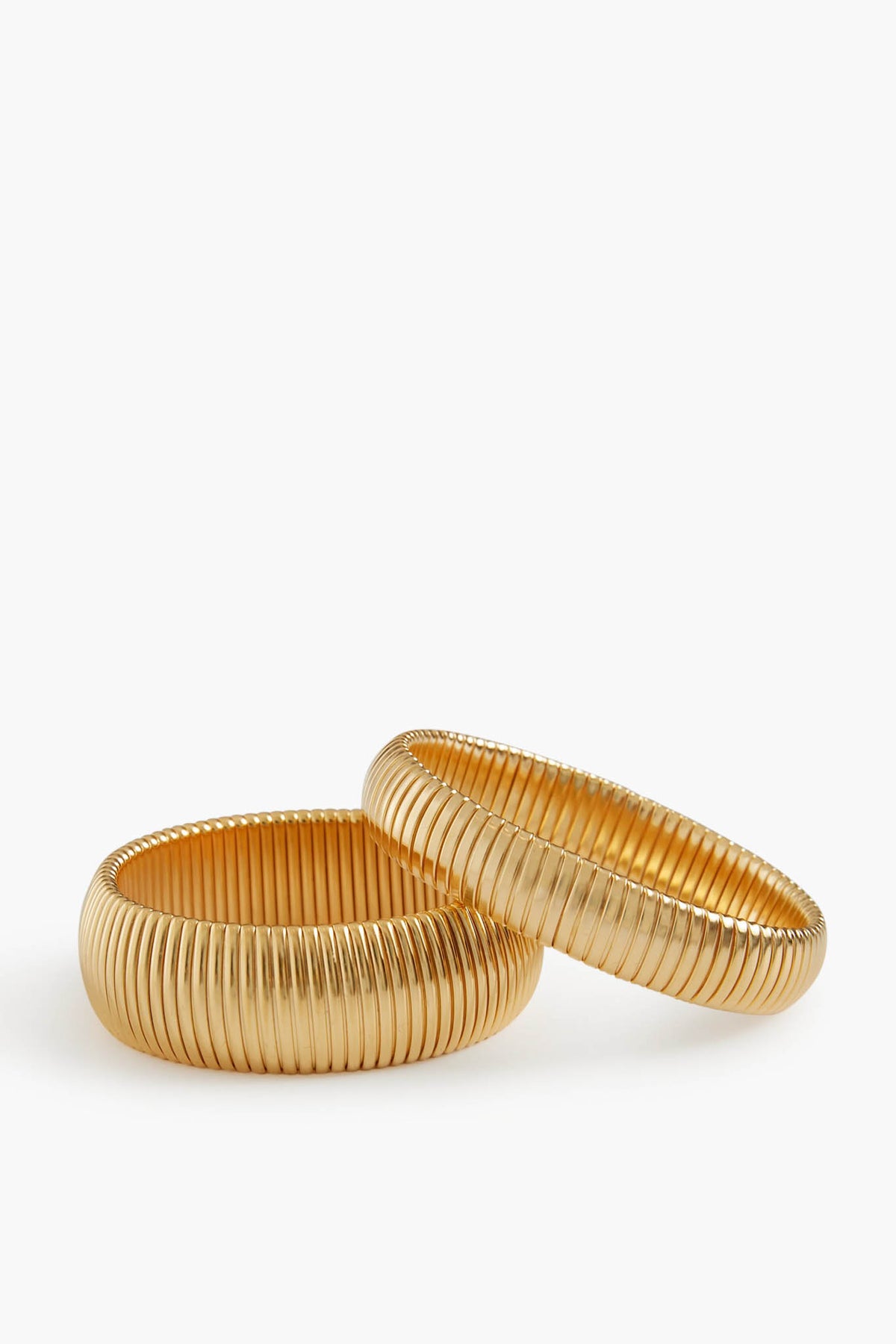 Two ribbed gold-plated brass bangles by Ben Amun are placed side by side, creating a striking statement jewelry piece.