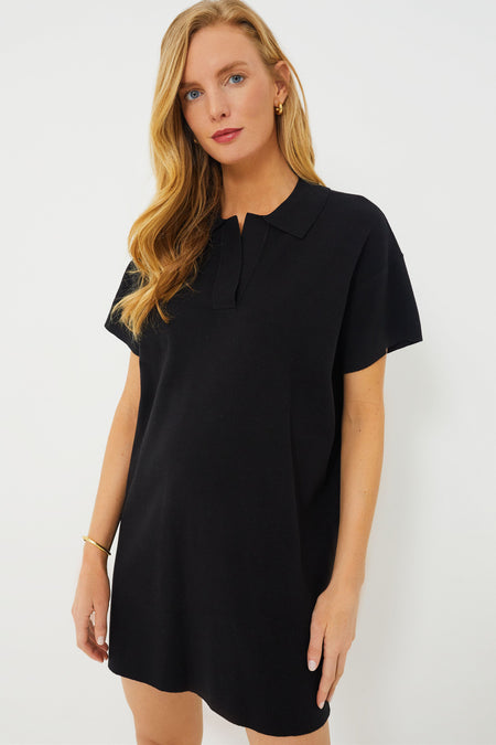 A woman wears the Tuckernuck Black Channing Polo Mini Dress, featuring short sleeves and a collared V-neckline, styled with loose hair and minimal accessories.
