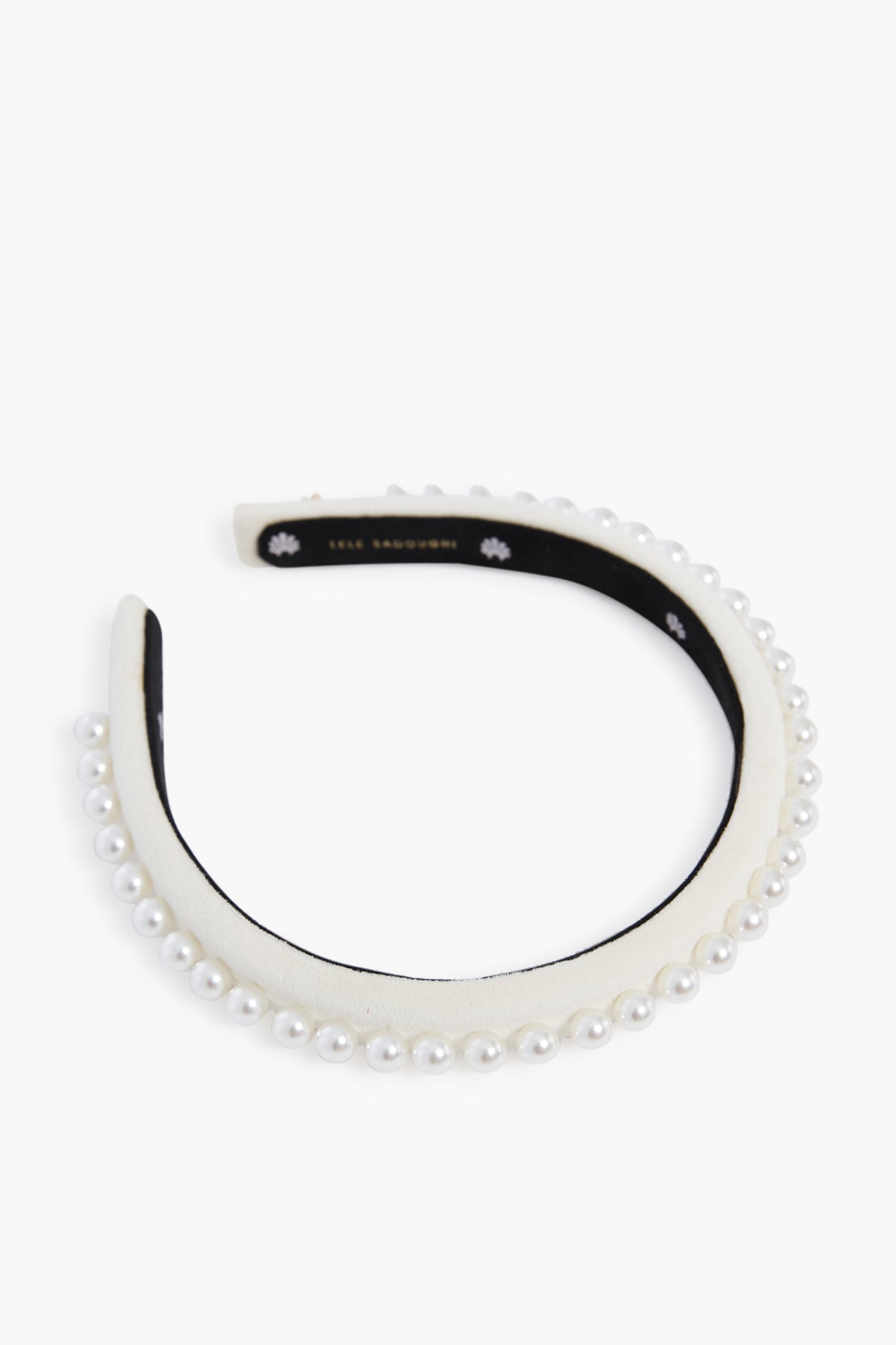 A Lele Sadoughi-inspired headband featuring a row of faux pearls, delicate floral accents, and a black inner lining.