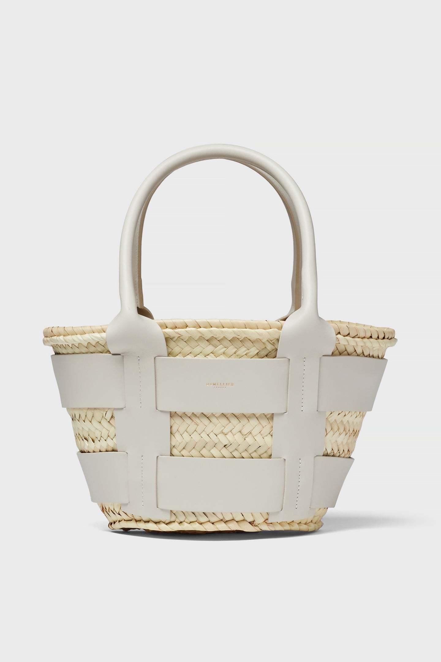 The Demellier woven straw raffia bag features wide white leather straps and handles, making it a chic mini tote perfect for everyday use.