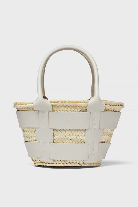 The Demellier woven straw raffia bag features wide white leather straps and handles, making it a chic mini tote perfect for everyday use.