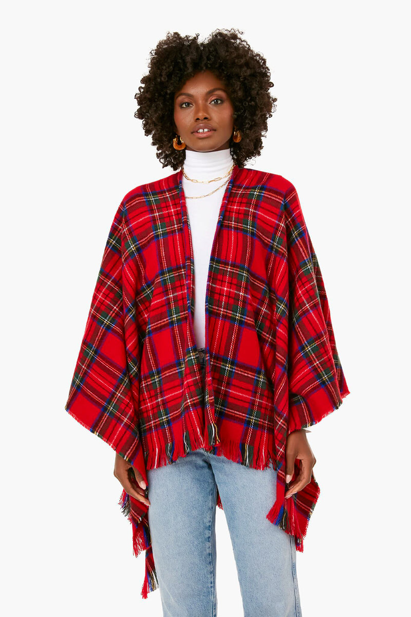 A woman creates a cozy and stylish look by wearing a David and Young red tartan poncho over a white turtleneck and light blue jeans.
