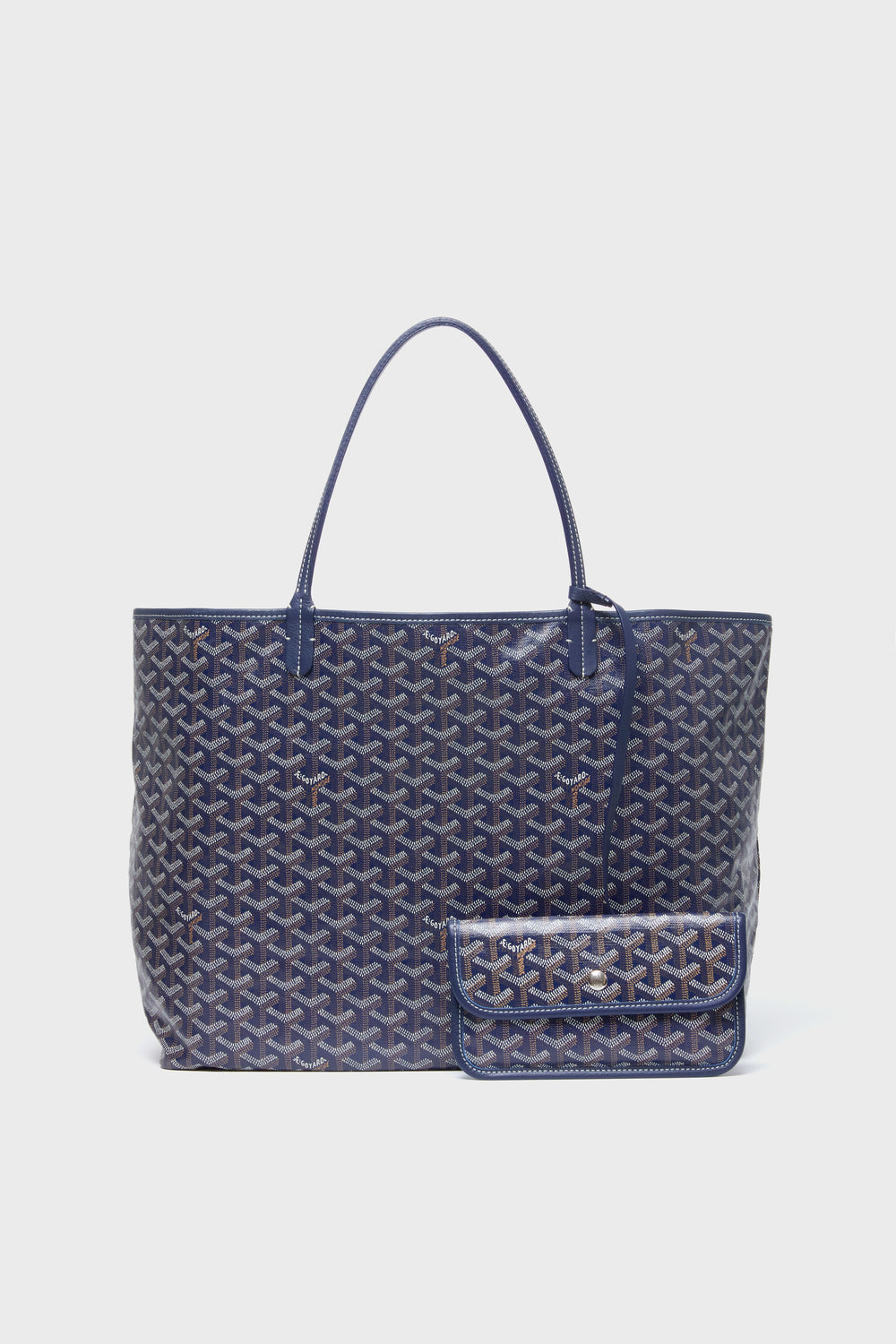 A large blue tote from the Tuckernuck Archive Collection features a geometric pattern on canvas, double handles, and a structured shape, paired with a matching small pouch.