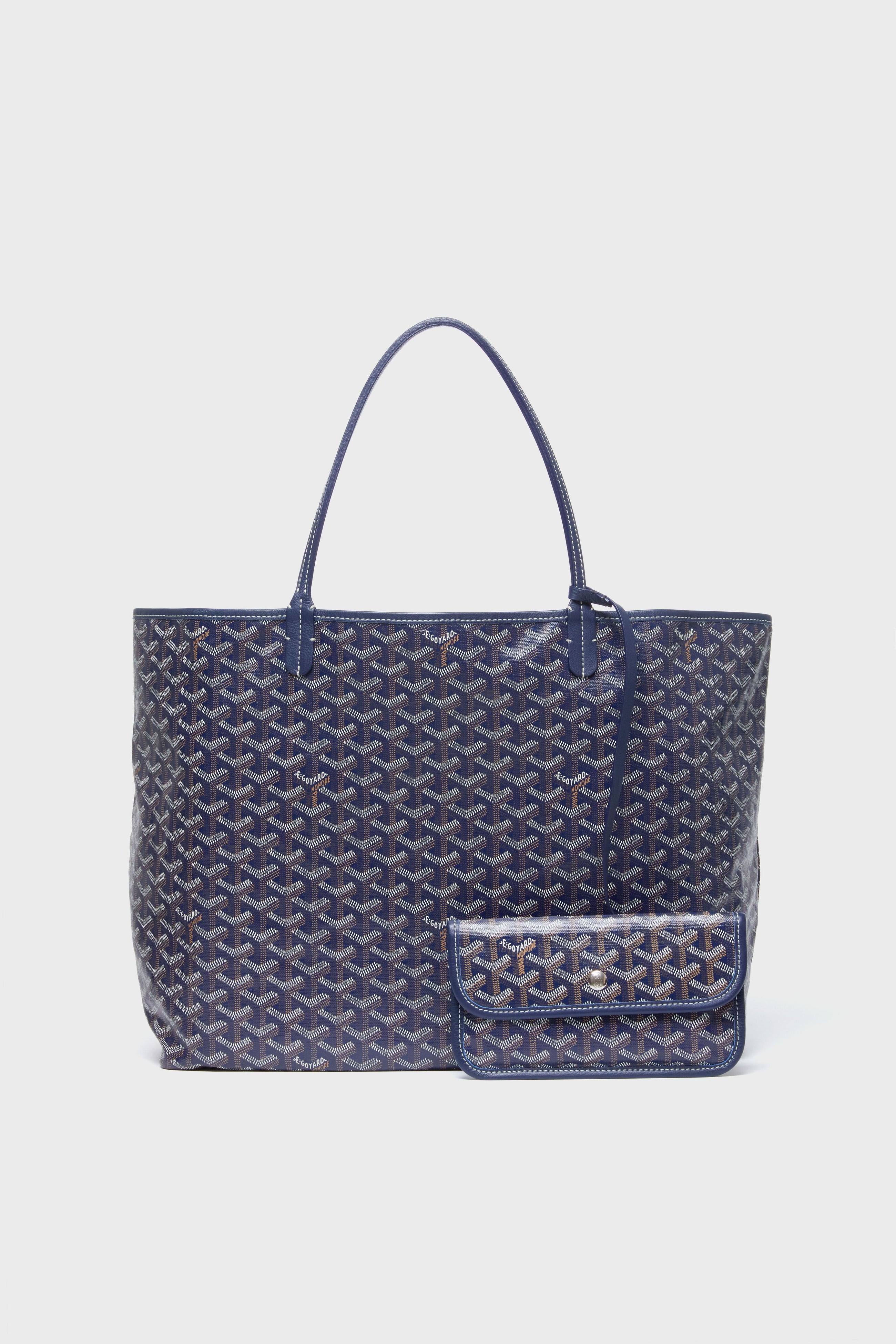 A large blue tote from the Tuckernuck Archive Collection features a geometric pattern on canvas, double handles, and a structured shape, paired with a matching small pouch.
