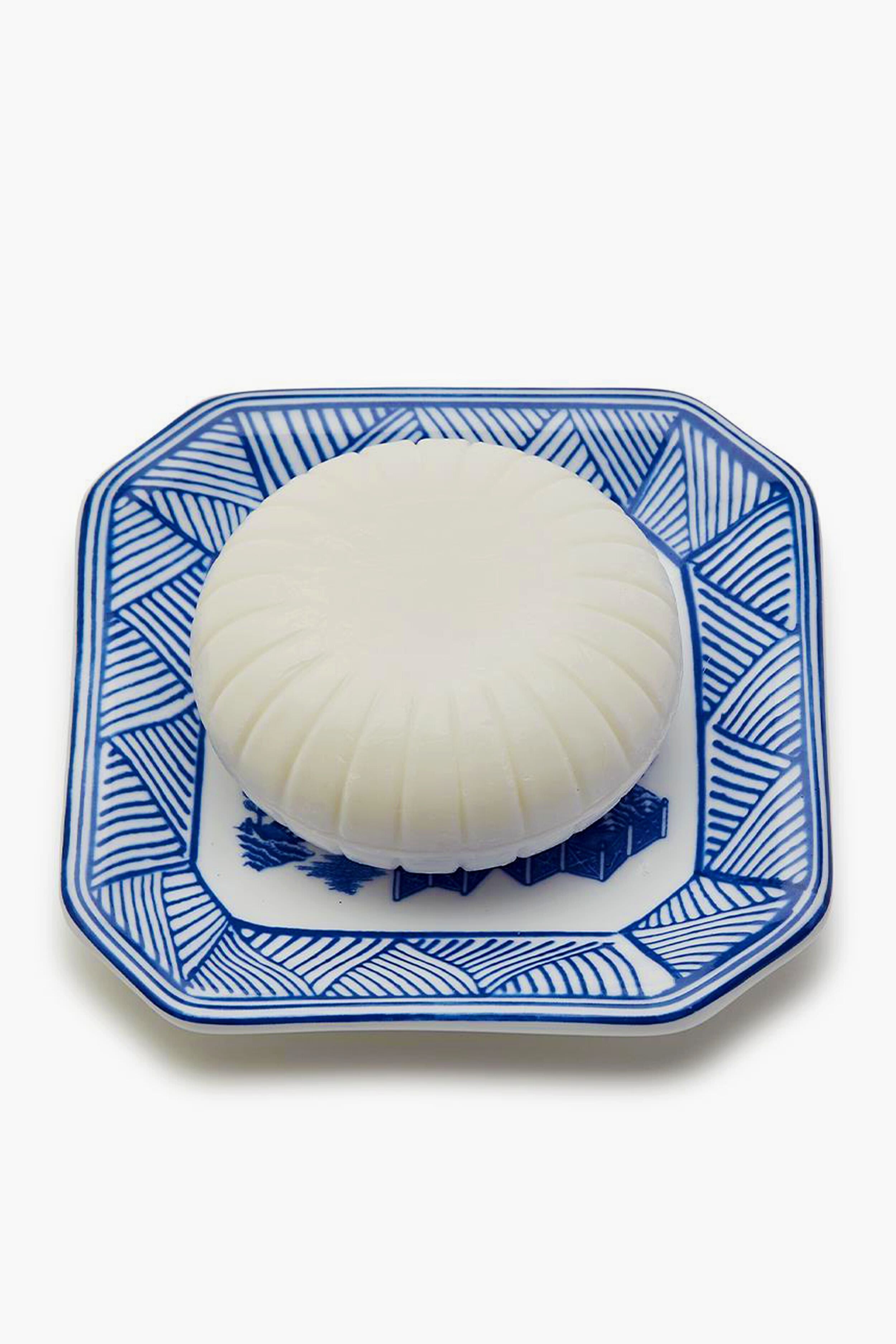 A Porcelain Tray by Two's Company holds a white object, accented with a hint of Sandalwood Scent.