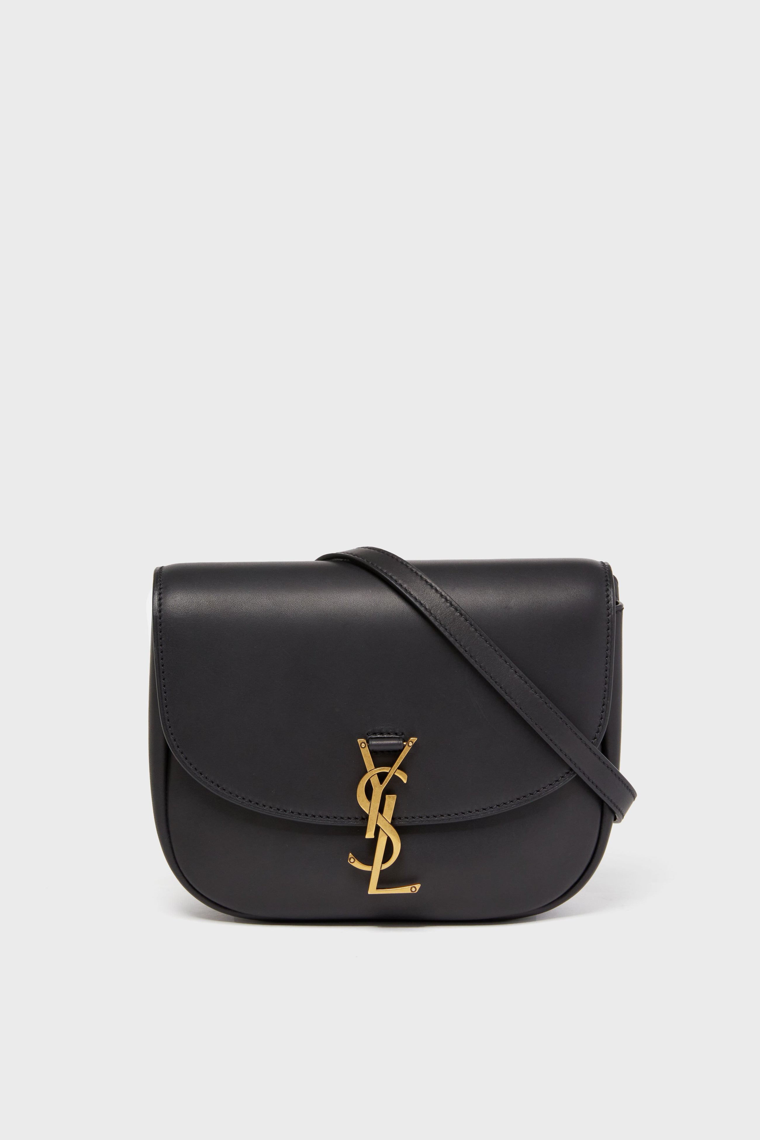 Black leather Tuckernuck Archive Collection Kaia Monogramme Bag featuring a gold logo on the front flap, perfect as a stylish crossbody accessory.