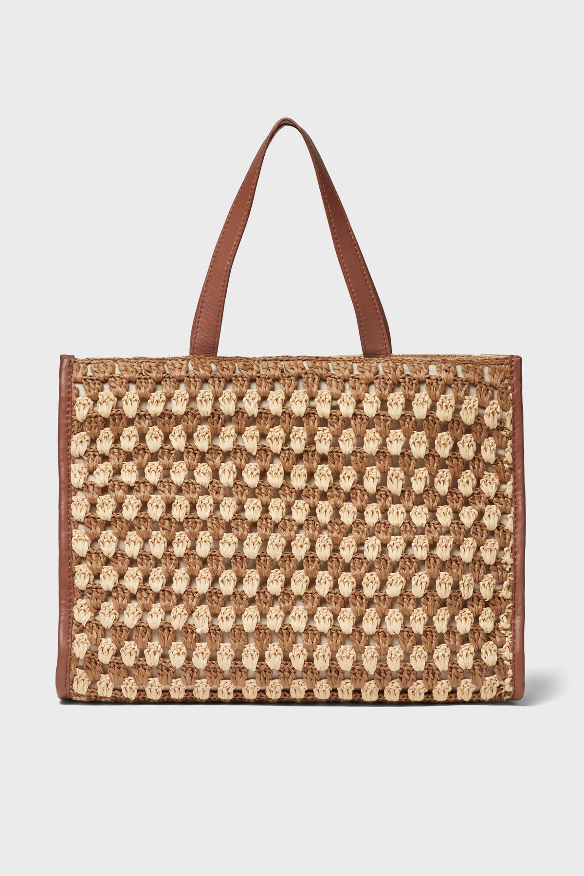 A rectangular woven straw tote bag by Loeffler Randall, featuring brown leather handles and trim for a touch of elegance.