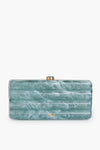 The Cult Gaia Seaspray Enid Clutch is a rectangular, blue-green marble-patterned accessory with a gold clasp and small gold logo—a unique statement piece.