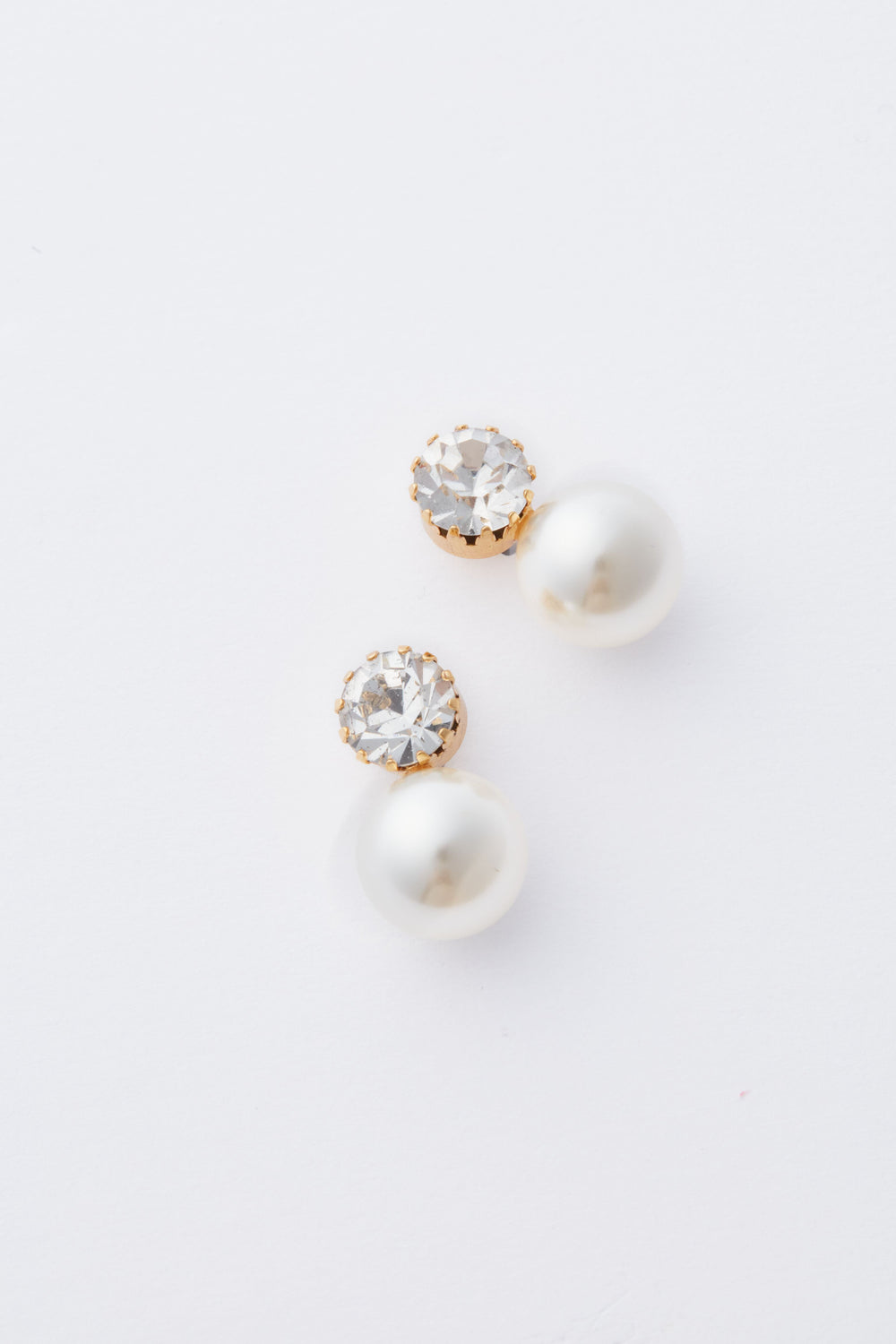 A pair of crystal pearl drop earrings by Jennifer Behr, featuring round clear gemstones set in gold with white pearls, showcasing the elegance of Antique Gold Ines Earrings.