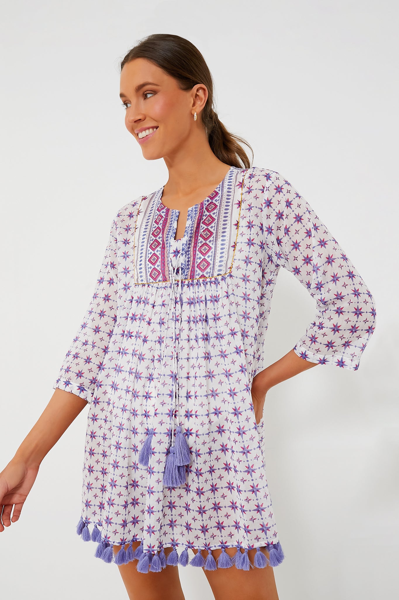 A woman wears a Ro's Garden cotton cover-up featuring purple star patterns, embroidered front details, and tassels on the hem and neckline—ideal as a vacation-ready tunic.