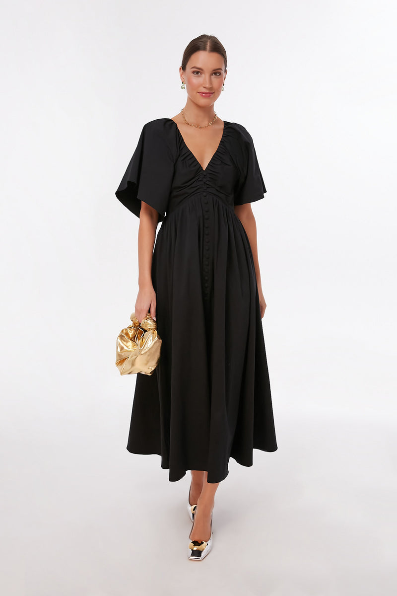 A woman in a black Pomander Place Viviana Maxi Dress with a V-neckline.