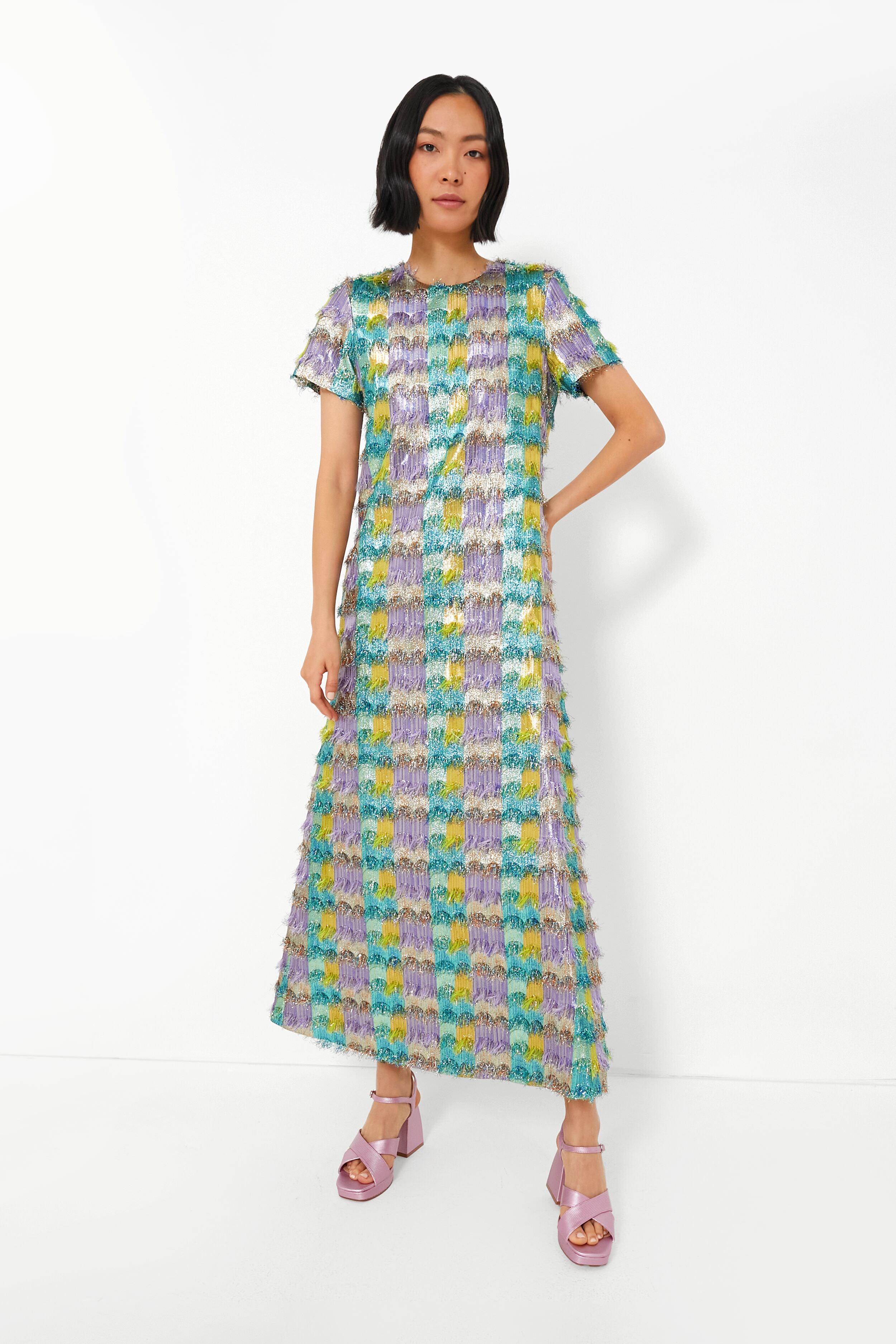 A woman wears a La DoubleJ Pharaoh Swing Dress with a colorful geometric jacquard pattern and light purple platform heels.