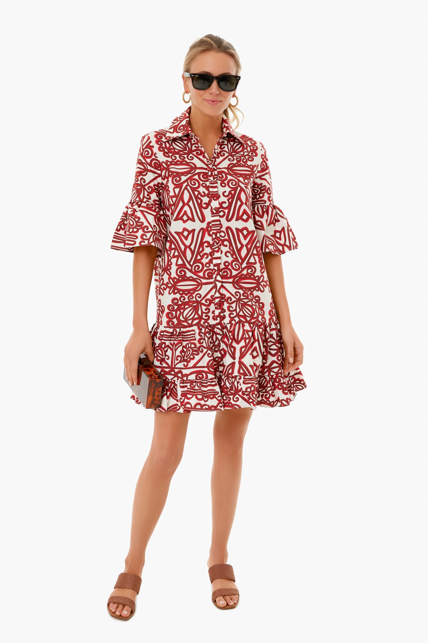 A woman stands confidently in a La DoubleJ red and white cotton poplin dress, paired with brown sandals, sunglasses, and a small clutch. This stylish Italian-made look is from La DoubleJ.