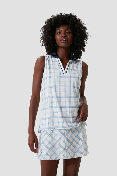 A woman wears a sleeveless, collared, light blue and white plaid Tnuck Sport Sleeveless Caroline Polo and matching skirt, both made with UPF 30 performance fabric.