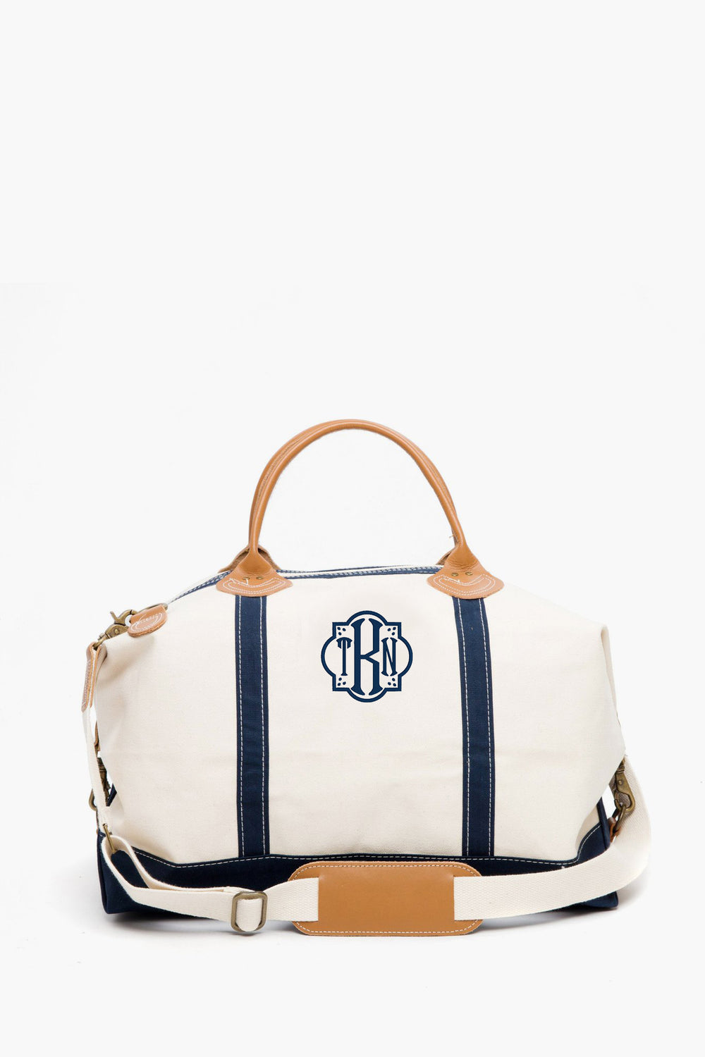 CB Station’s eco-friendly cotton canvas satchel features navy blue stripes, tan leather handles, a detachable shoulder strap, and a blue monogram logo on the front.