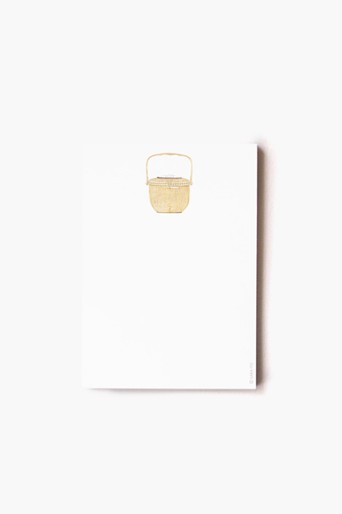 A white Sara Fitz Nantucket Basket Notepad features a small gold picnic basket illustration centered at the top. Made in the USA.