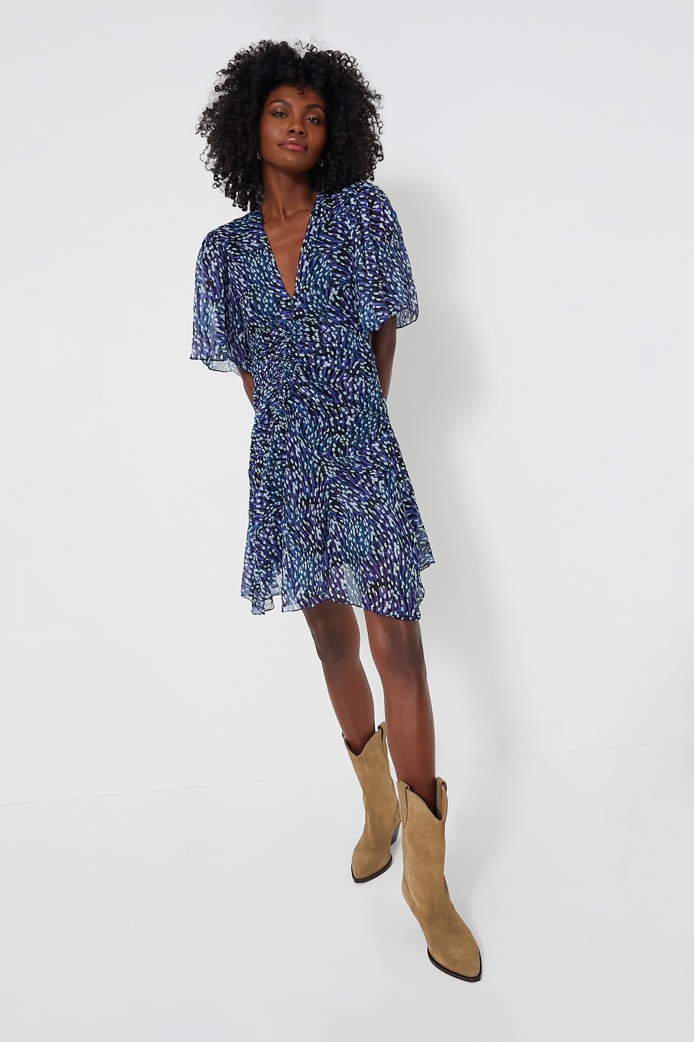 Woman wearing the Isabel Marant Etoile Midnight Vivienne Printed Chiffon mini dress with flutter sleeves and tan cowboy boots, channeling an Isabel Marant-inspired style.
