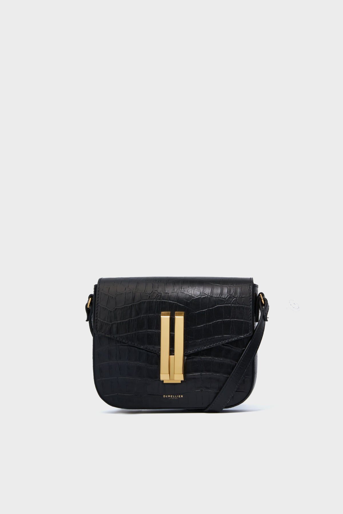 A Demellier Black Croc Small Vancouver Bag, a handcrafted leather handbag with a gold-tone rectangular clasp and adjustable crossbody strap, is displayed.