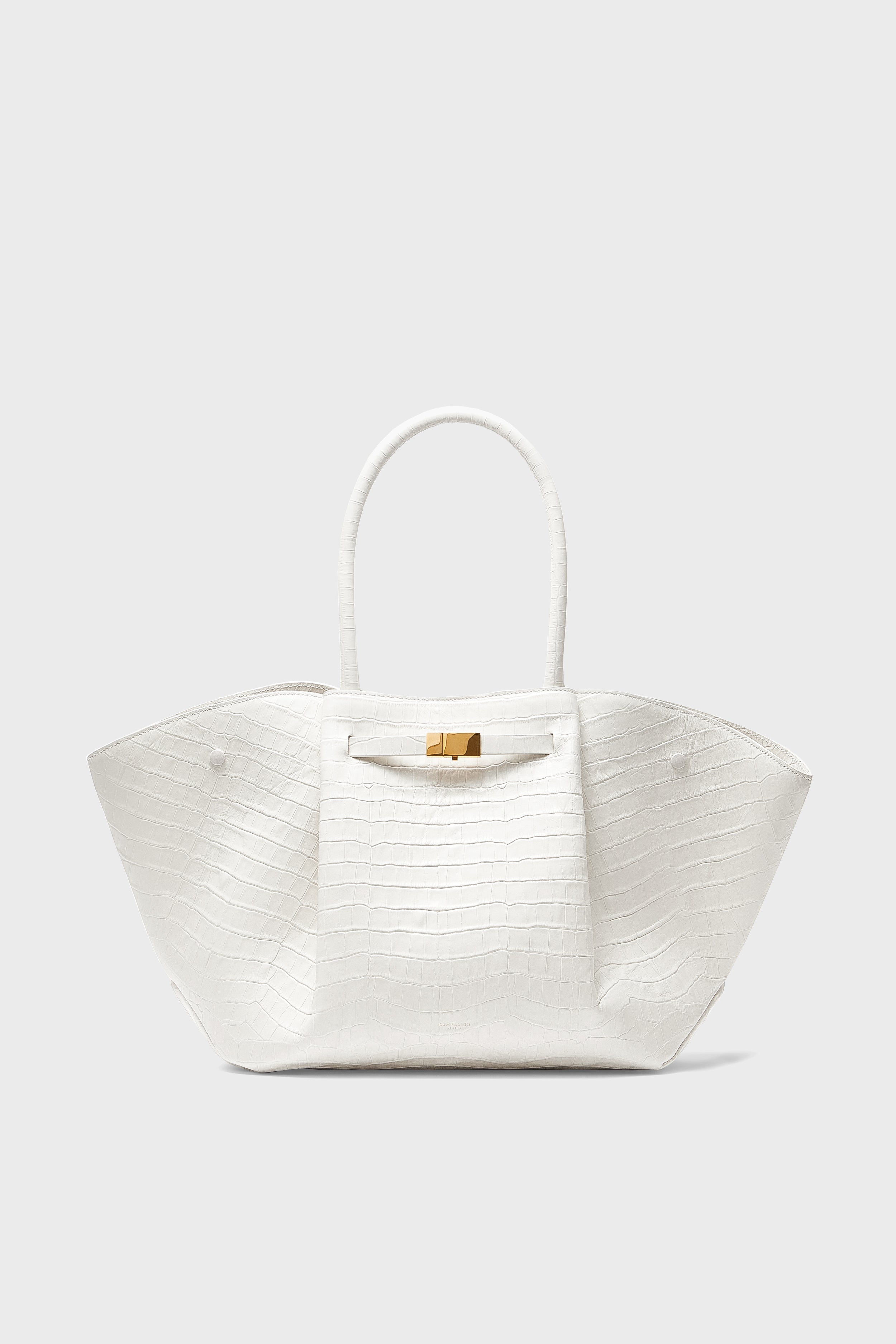 A white, croc-effect leather handbag by Demellier with two handles and a gold clasp, embodying the elegance of handcrafted Spanish design.
