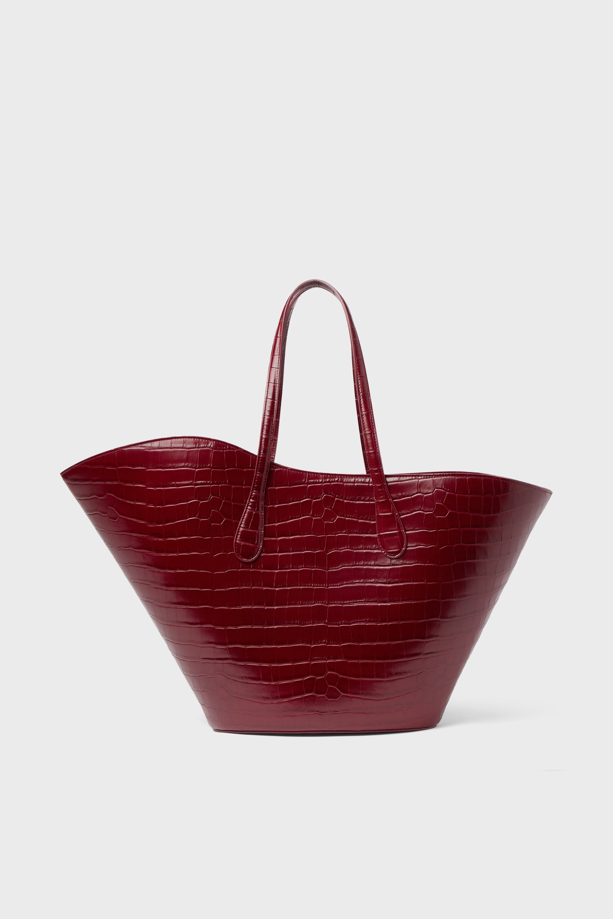 The Liffner tote is a spacious, structured bag with a dark red croc-embossed finish, featuring two handles and crafted in Scandinavian design.