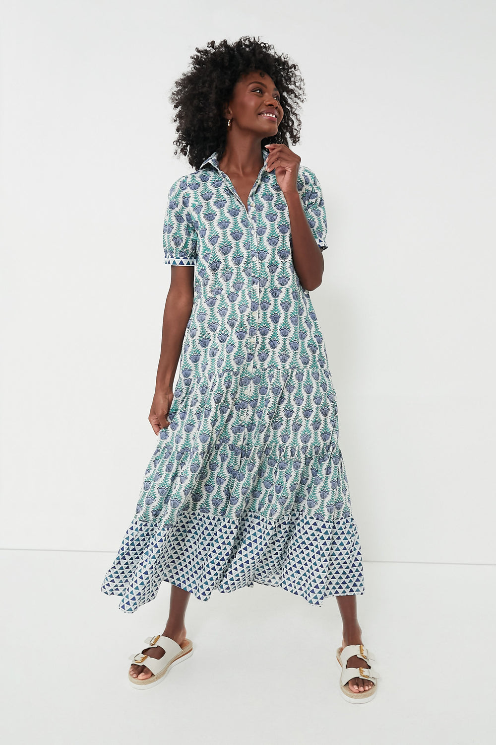 A woman wears a Marea patterned, button-down short-sleeve summer dress with white sandals, showcasing effortless style.