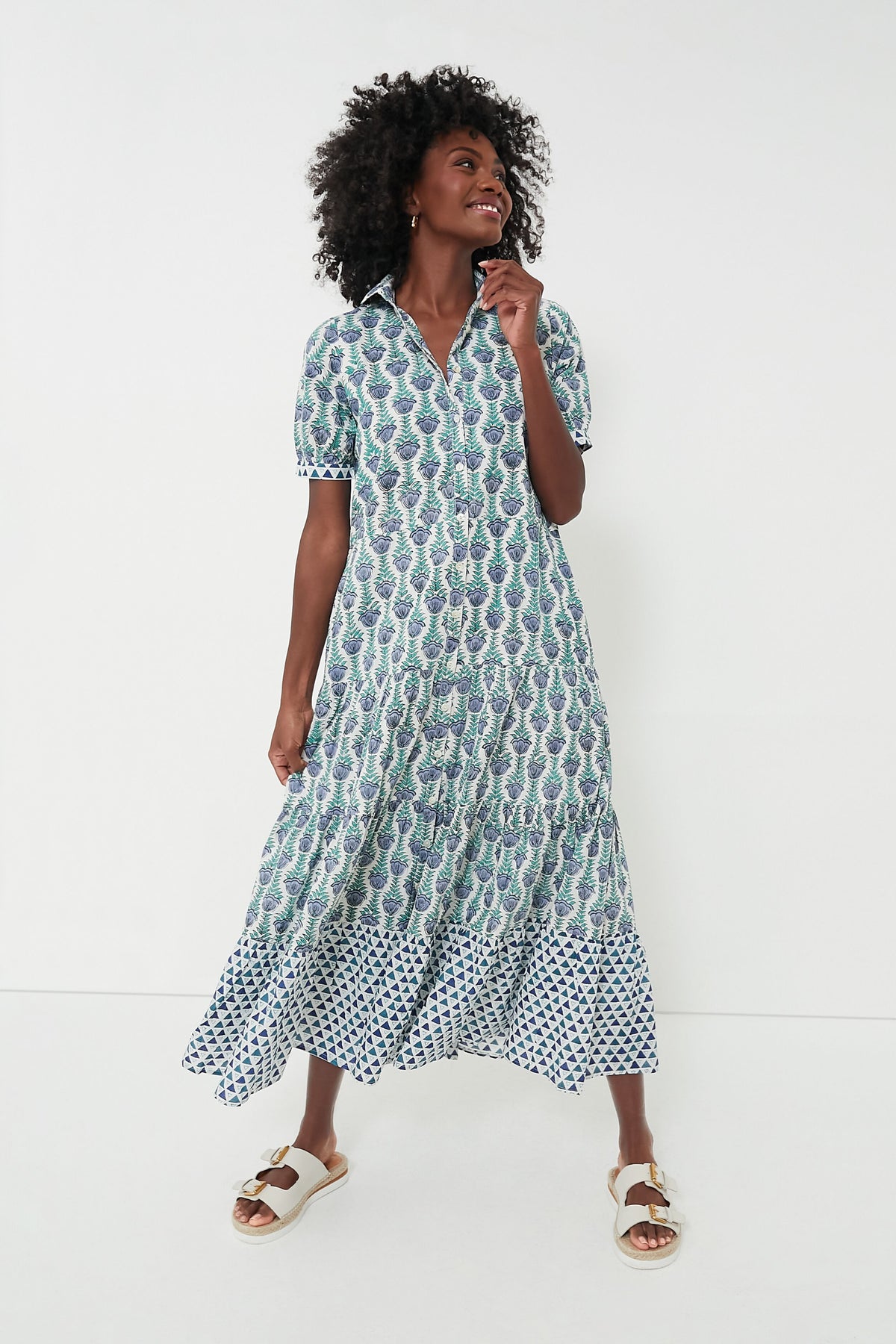 A woman wears a Marea patterned, button-down short-sleeve summer dress with white sandals, showcasing effortless style.