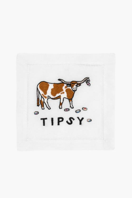 August Morgan’s white embroidered linen napkin features a brown and white longhorn cow, five tiny cups, and the word “TIPSY” underneath—a cheeky cocktail napkin perfect for lively gatherings.