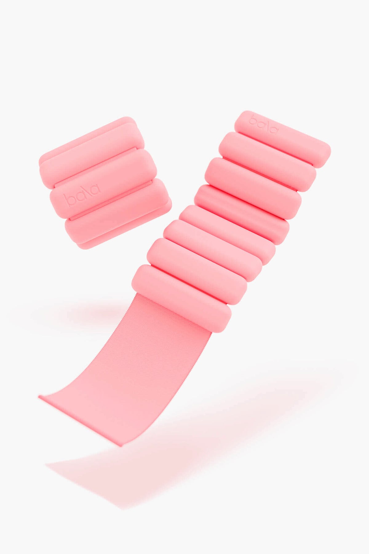 A pair of bala pink, adjustable wearable weights with segmented cylindrical sections—ideal fitness accessories for wrists or ankles.