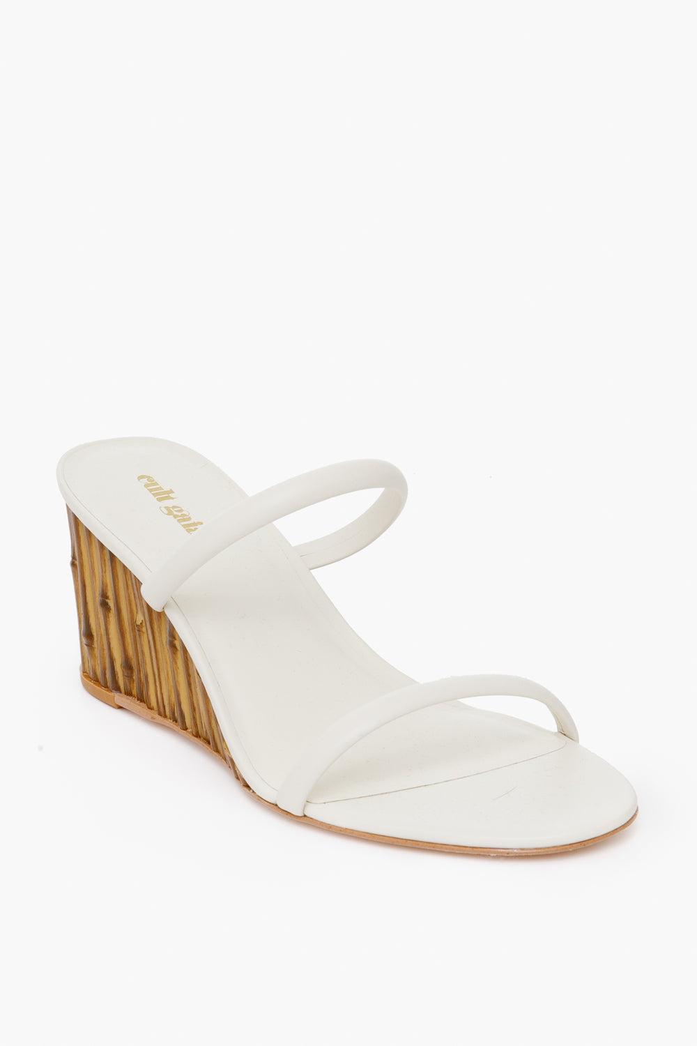 A chic white open-toe sandal by Cult Gaia, featuring two slender straps and a bamboo-effect wedge heel, elegantly showcased.