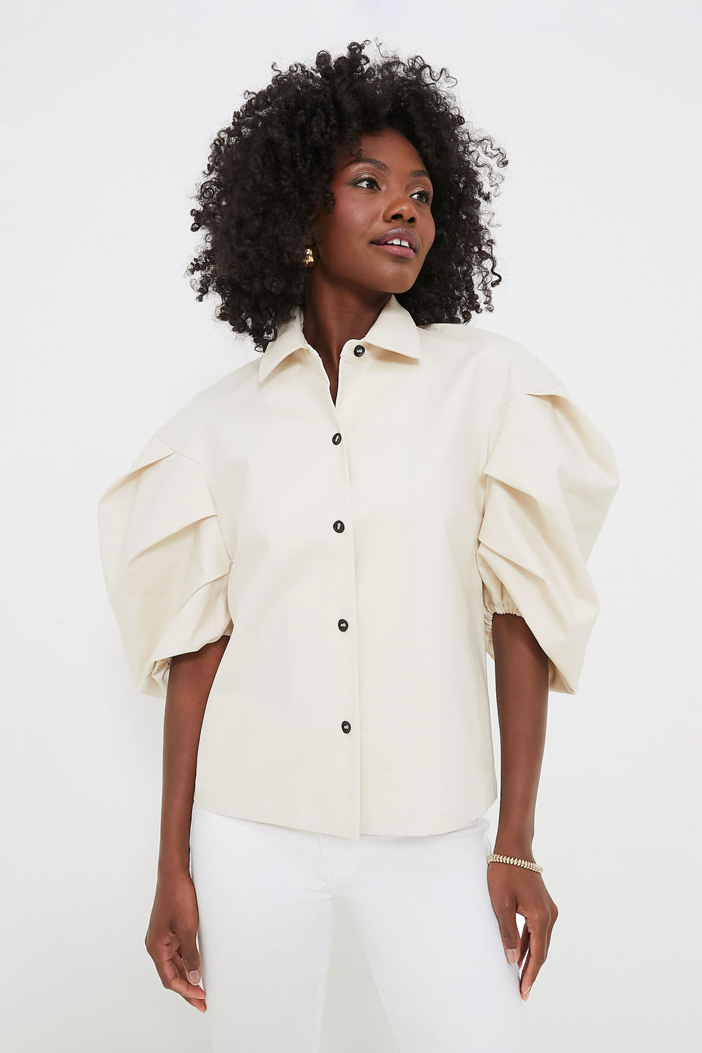 A woman models a chic ALEXIS cream-colored puff sleeve top with white pants, showcasing stylish womenswear.