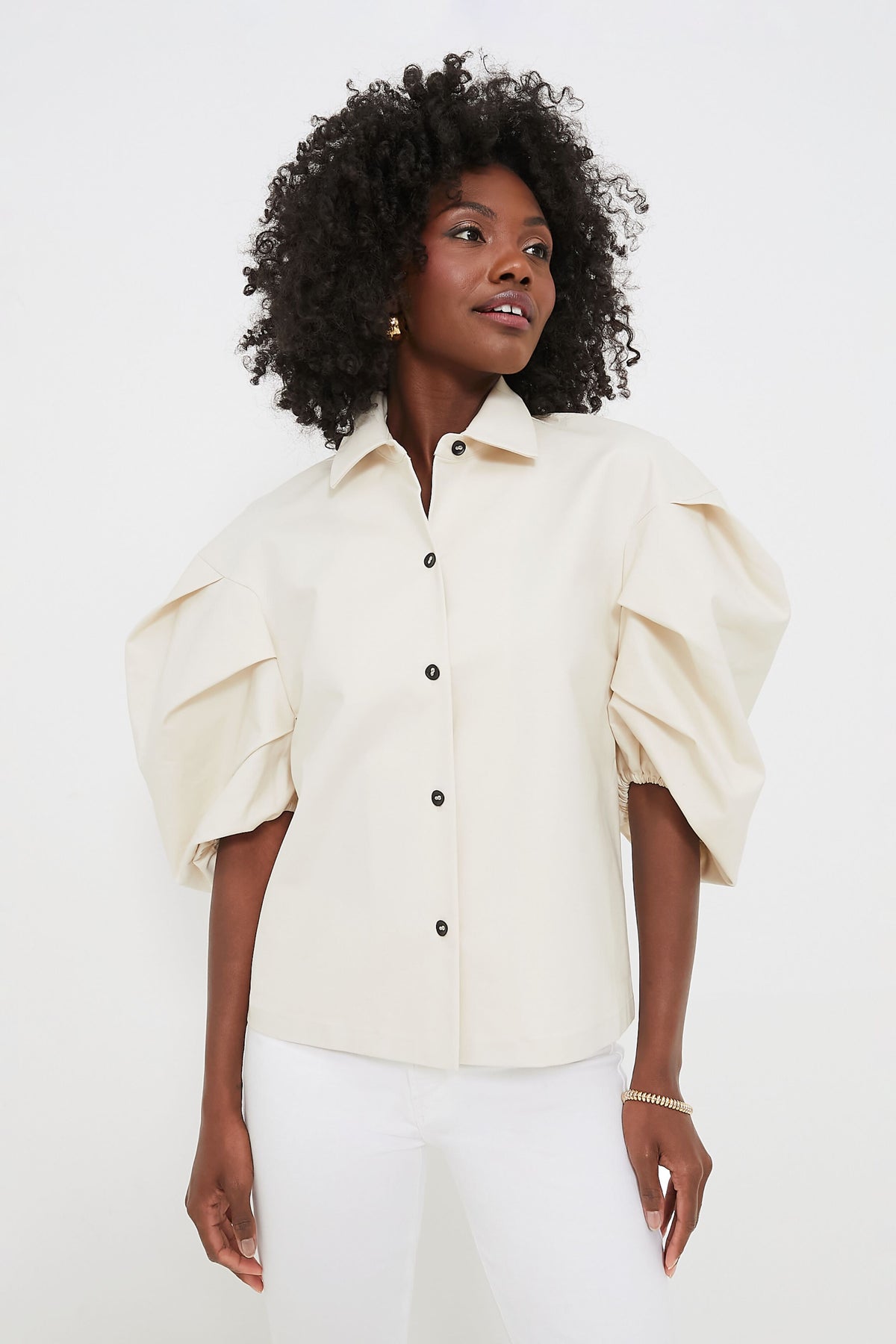 A woman models a chic ALEXIS cream-colored puff sleeve top with white pants, showcasing stylish womenswear.