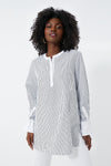 A woman wears a HARSHMAN long-sleeve black-and-white vertically striped Zoe Popover blouse with a collarless neckline and white cuffs, showcasing classic womenswear style.