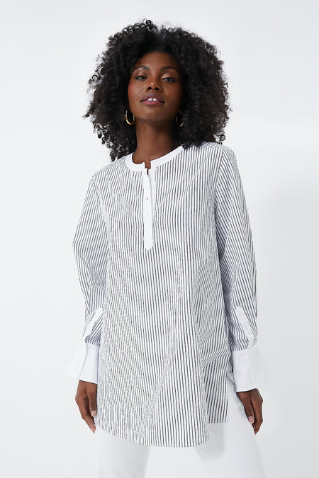 A woman wears a HARSHMAN long-sleeve black-and-white vertically striped Zoe Popover blouse with a collarless neckline and white cuffs, showcasing classic womenswear style.