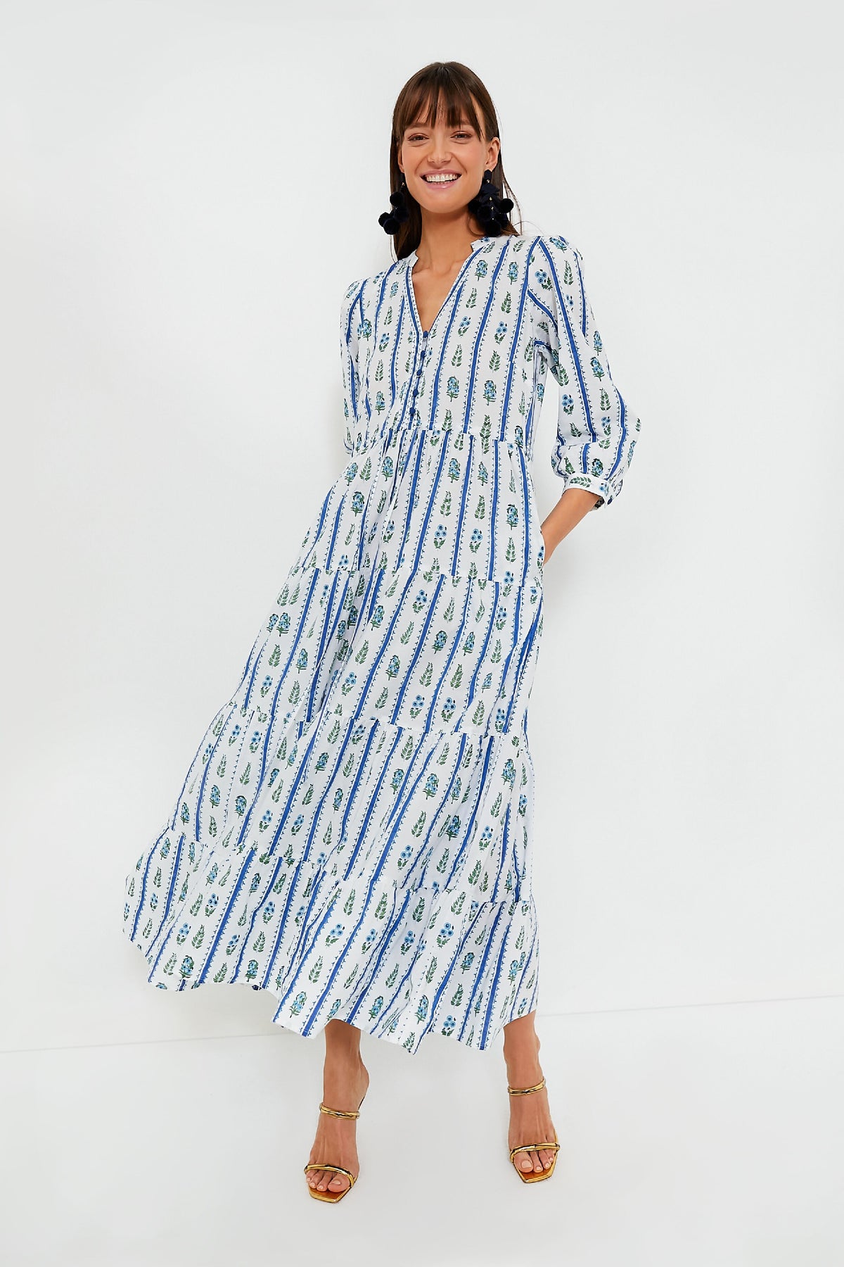 A woman wears a Pink City Prints bohemian midi dress with blue and green patterns and gold strappy heels.