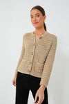 A woman wears a ba&sh textured beige French aesthetic sweater with gold buttons and black pants.