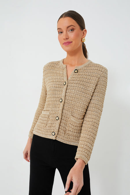 A woman wears a ba&sh textured beige French aesthetic sweater with gold buttons and black pants.