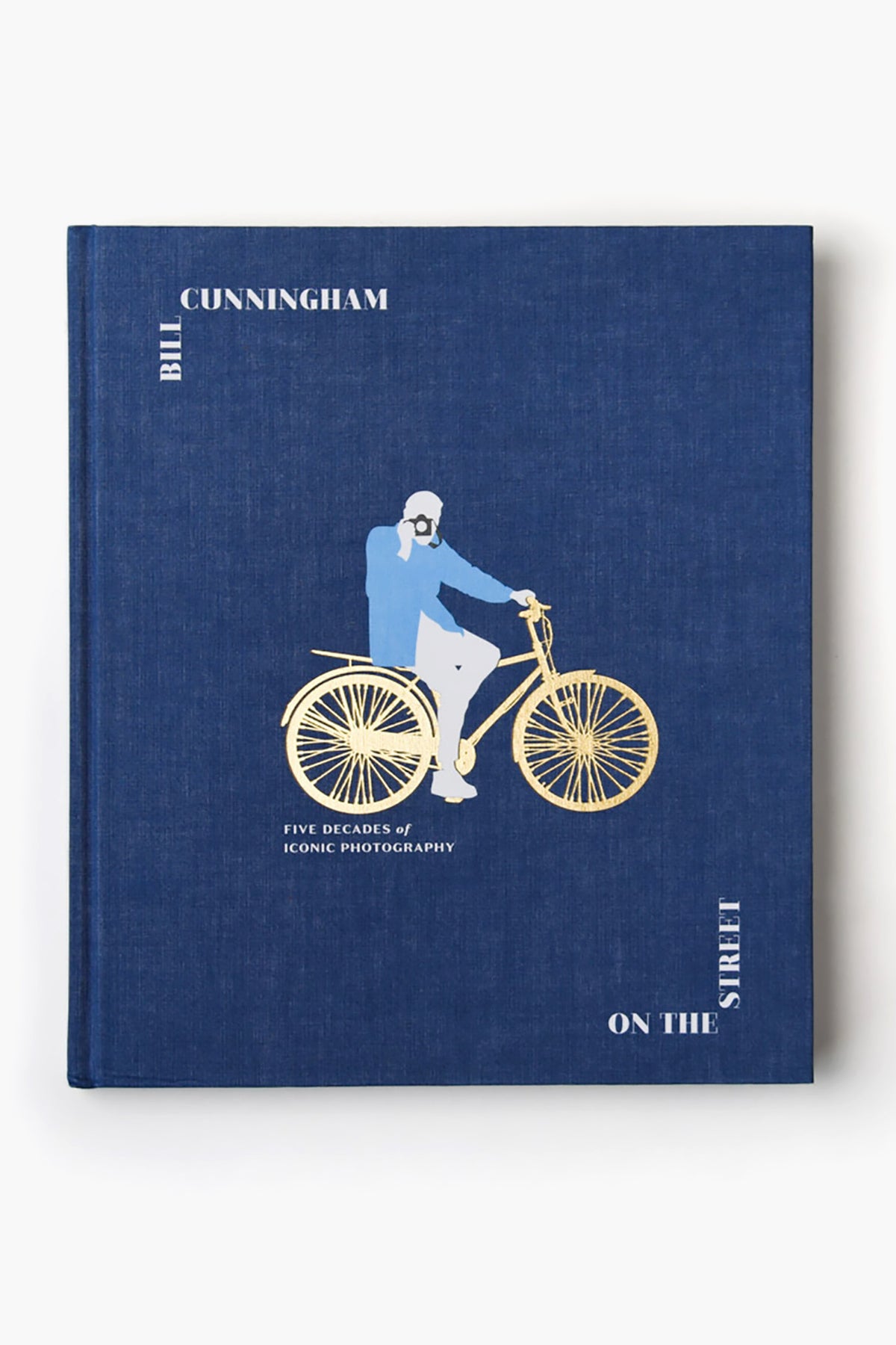 Blue book cover titled "Bill Cunningham: On The Street" by Rizzoli, featuring a man on a bicycle and the subtitle "Five Decades of Iconic Photography," celebrating New York City fashion and Bill Cunningham's photography.