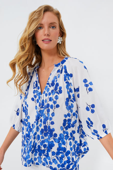Woman wears the Ro's Garden Leaf Marcia Top—a relaxed-fit cotton blouse in white and blue floral print with a V-neckline and loose sleeves, ideal for luxury travel.