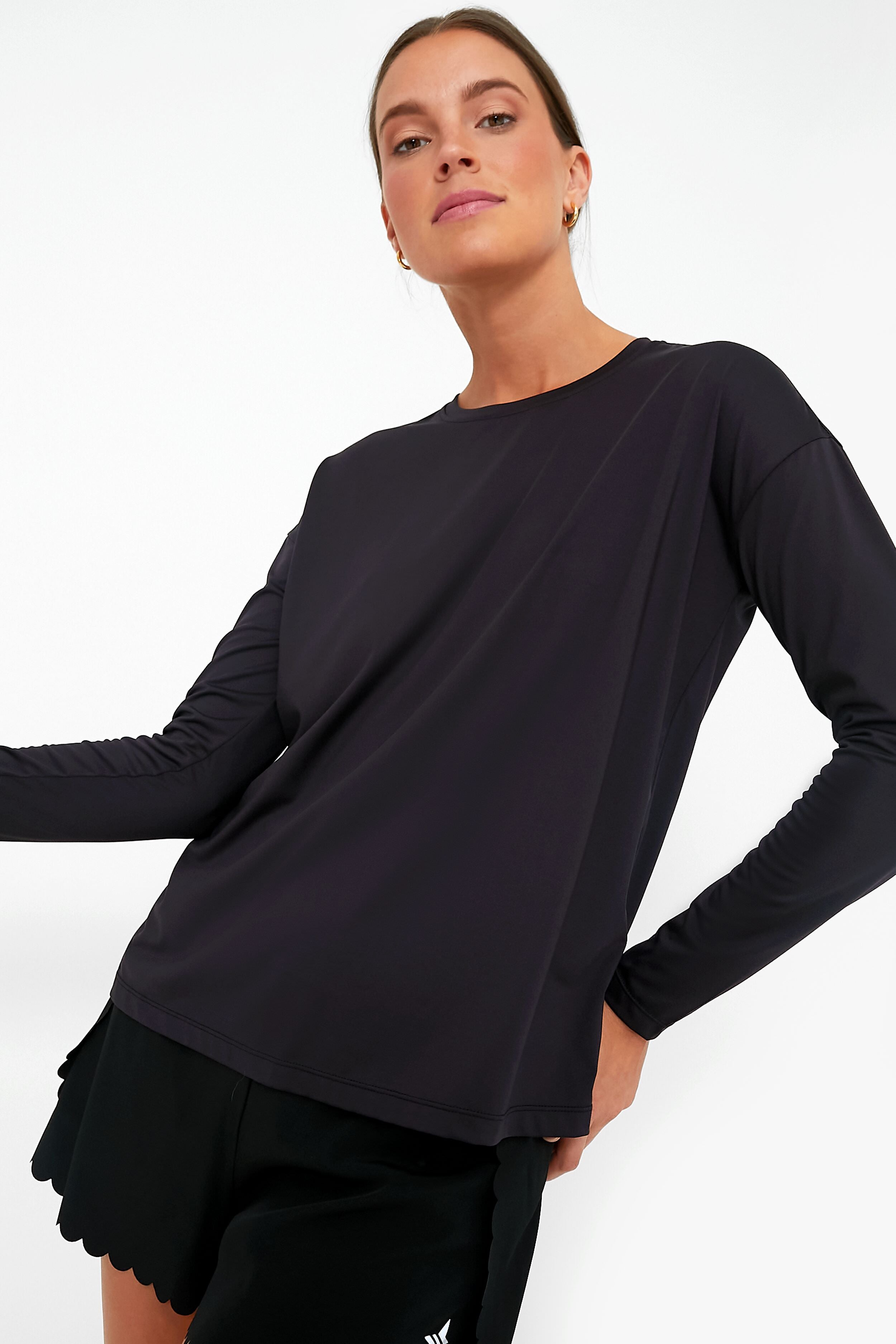 A person confidently poses in Tnuck Sport’s moisture-wicking long sleeve tee and black shorts, highlighting stylish comfort and SPF protection.
