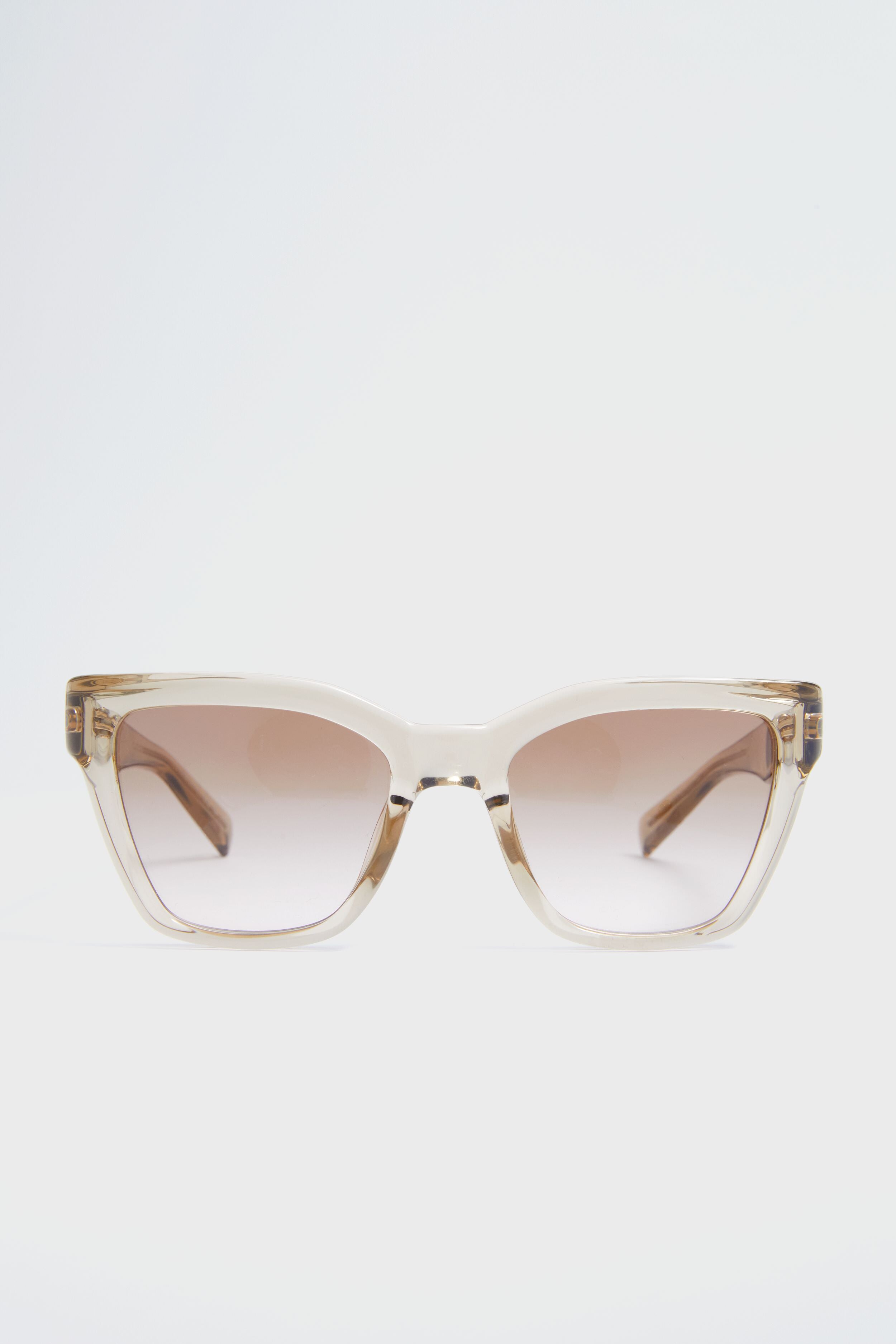 A pair of oversized cat eye sunglasses by Saint Laurent in beige, featuring gradient brown lenses and a chic design.