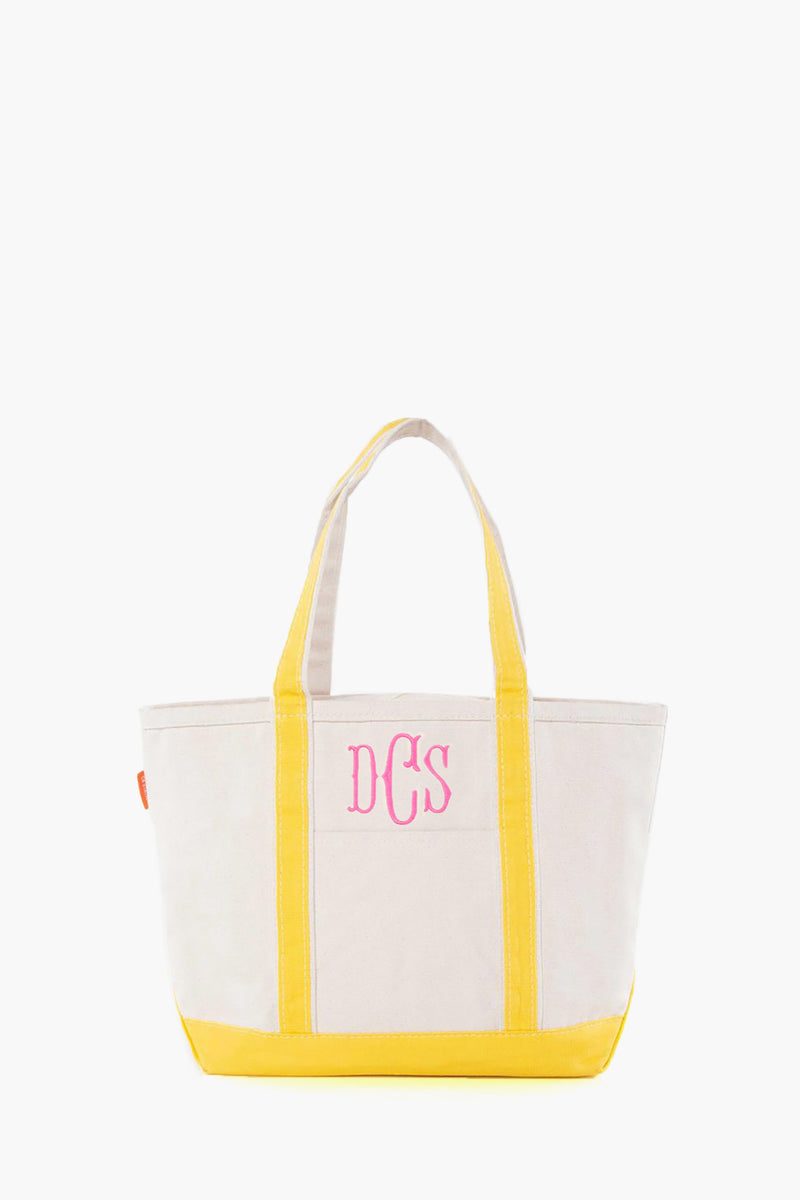 The CB Station beige canvas tote bag features yellow handles and trim, plus pink DCS monogram initials on the front. This stylish, reusable bag is ideal for everyday use.