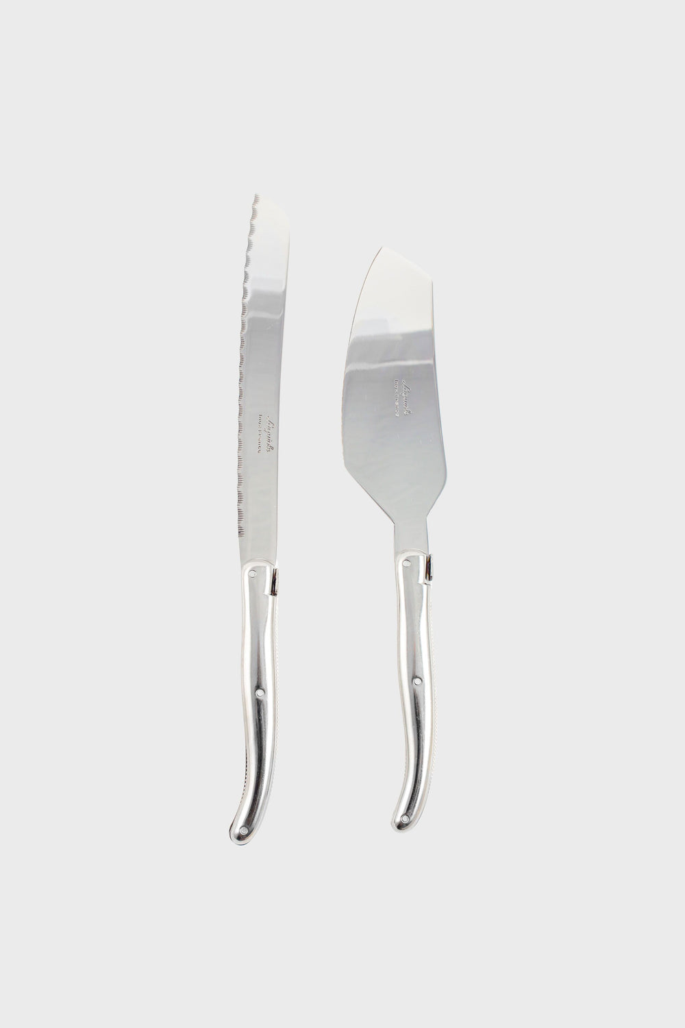 A Laguiole silver bread knife and cheese knife with matching curved handles are placed side by side, highlighting the brand's French craftsmanship and elegant design.