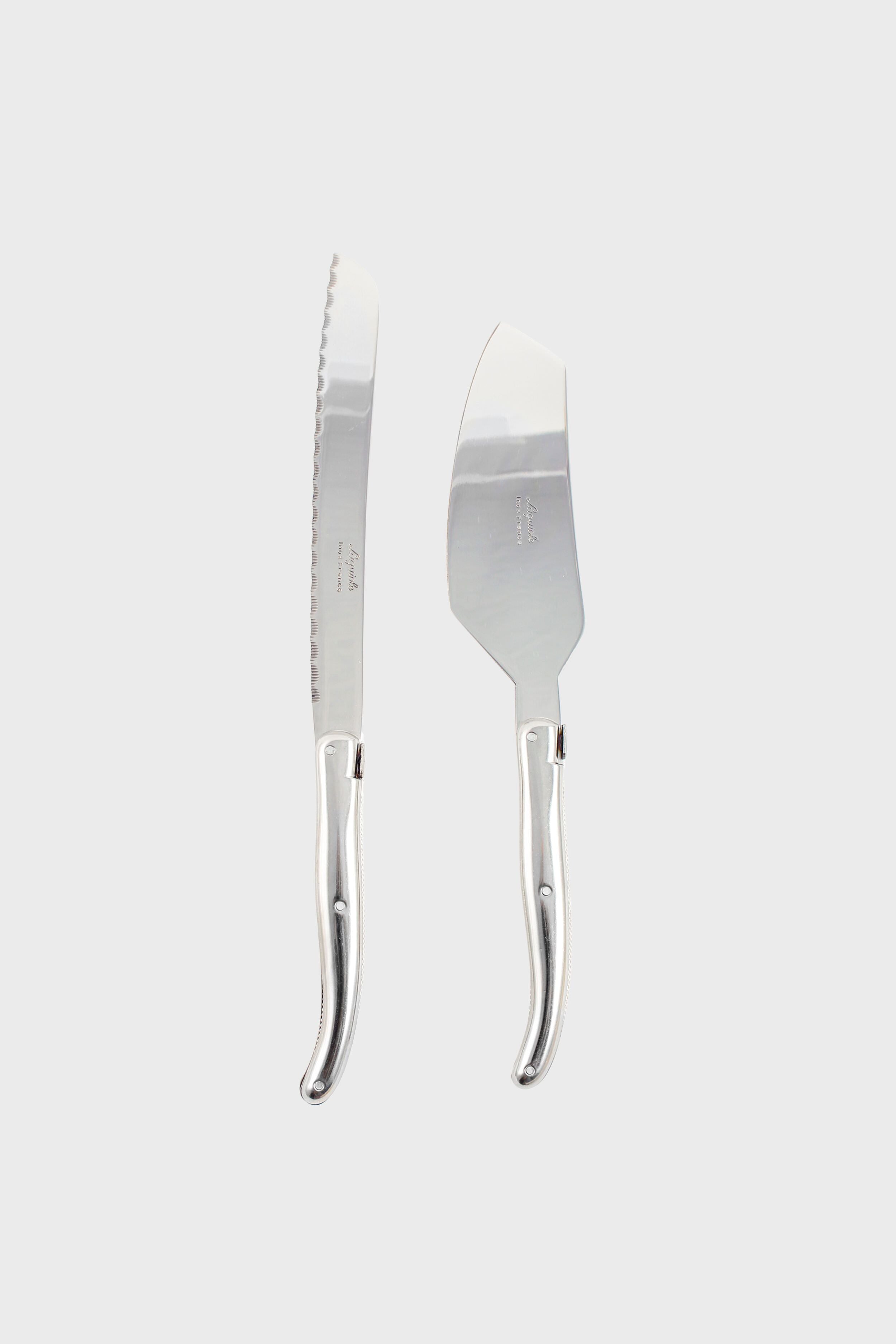 A Laguiole silver bread knife and cheese knife with matching curved handles are placed side by side, highlighting the brand's French craftsmanship and elegant design.