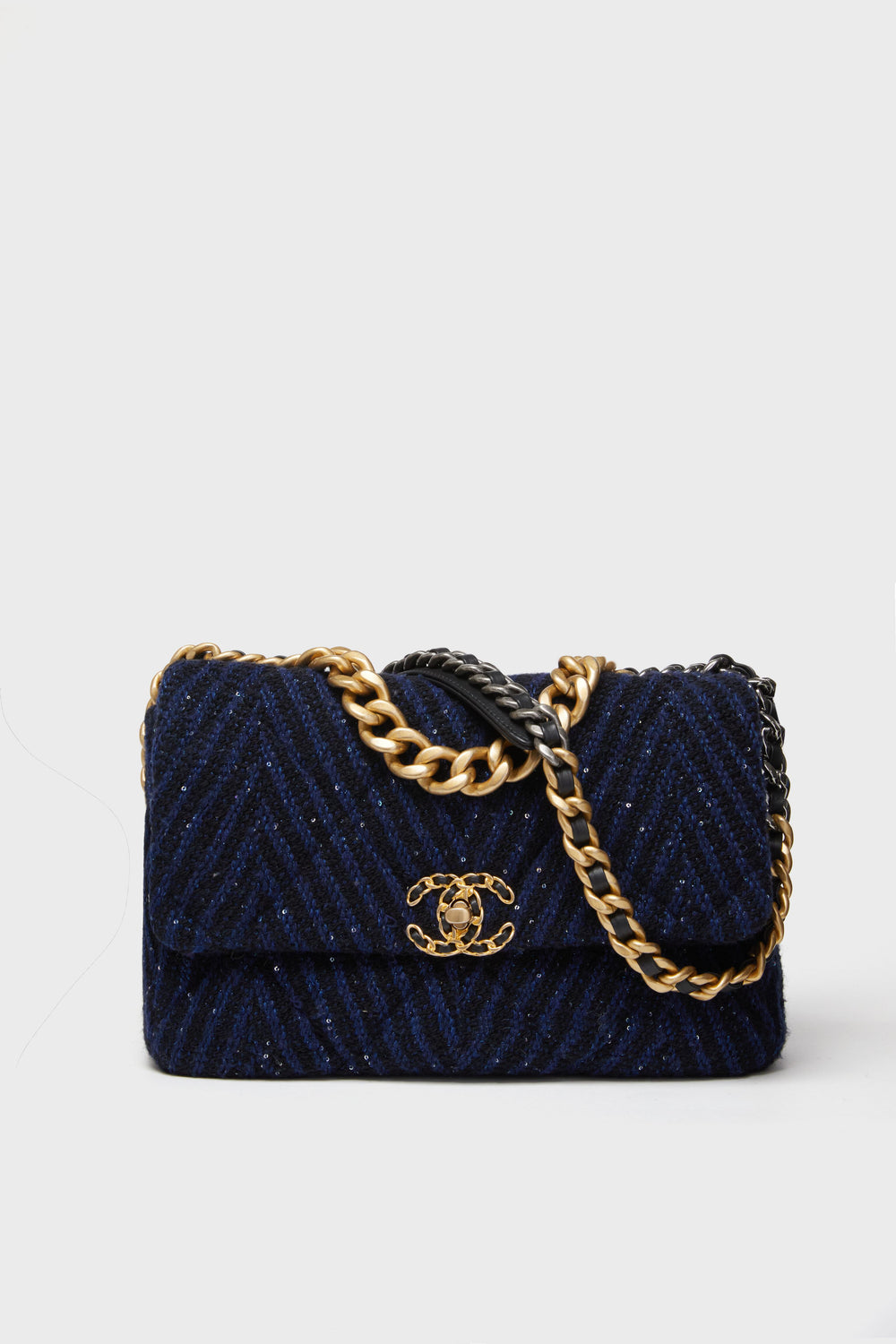 A navy blue quilted bag from the Tuckernuck Archive Collection, featuring a gold and black chain strap and a gold interlocking CC logo on the front flap.