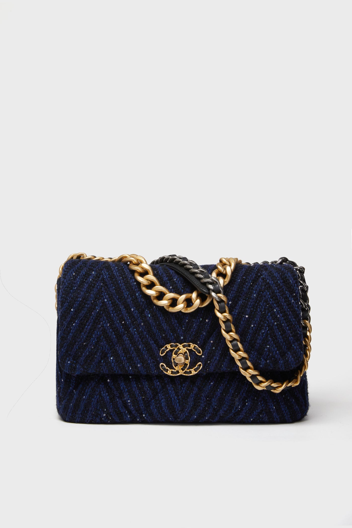 A navy blue quilted bag from the Tuckernuck Archive Collection, featuring a gold and black chain strap and a gold interlocking CC logo on the front flap.