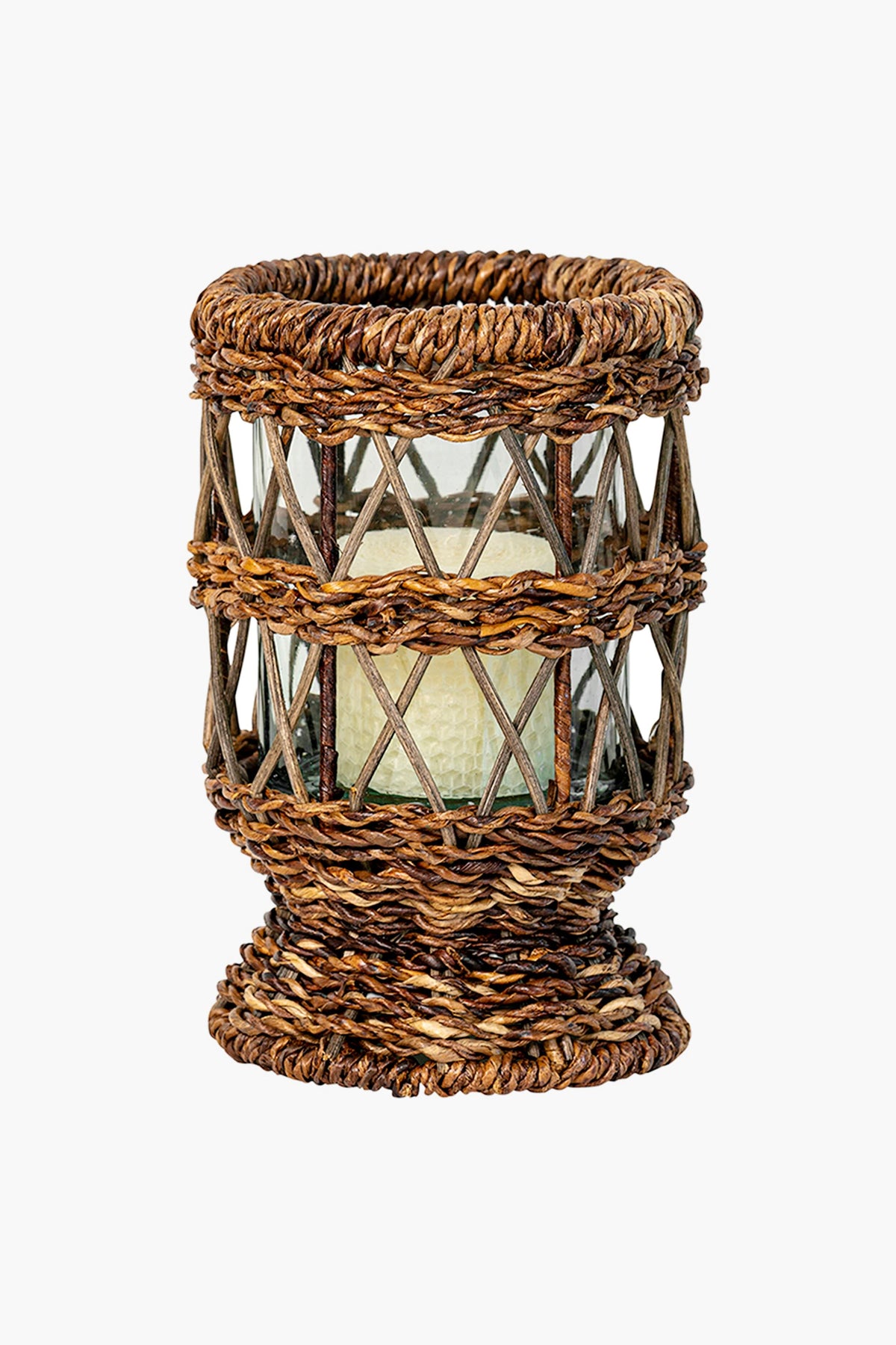 A glass candle holder by Juliska featuring a decorative brown woven wicker cover, ideal as a rustic table centerpiece or handwoven abaca accent for stylish decor.