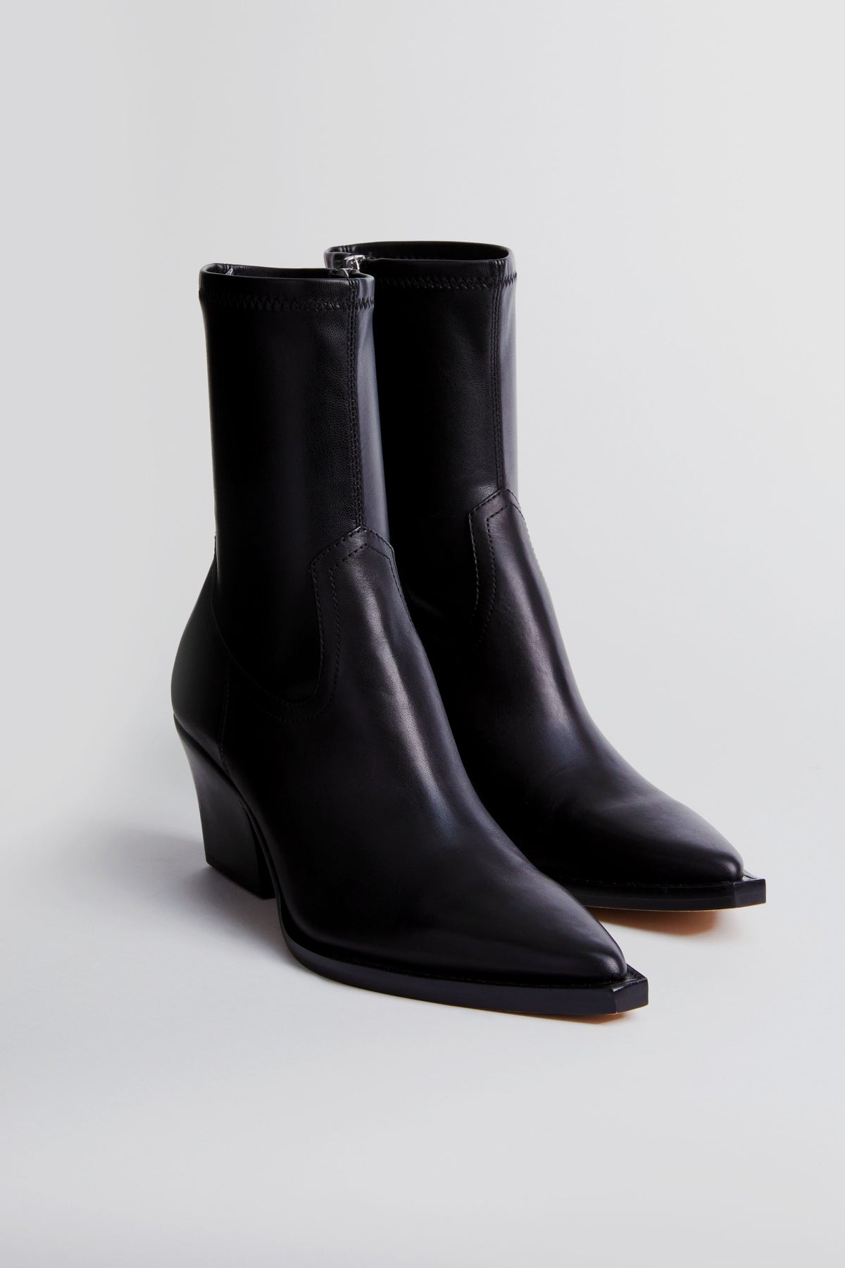 A pair of black Dolce Vita Rutger booties featuring a pointed toe and chunky heel, crafted from premium leather.