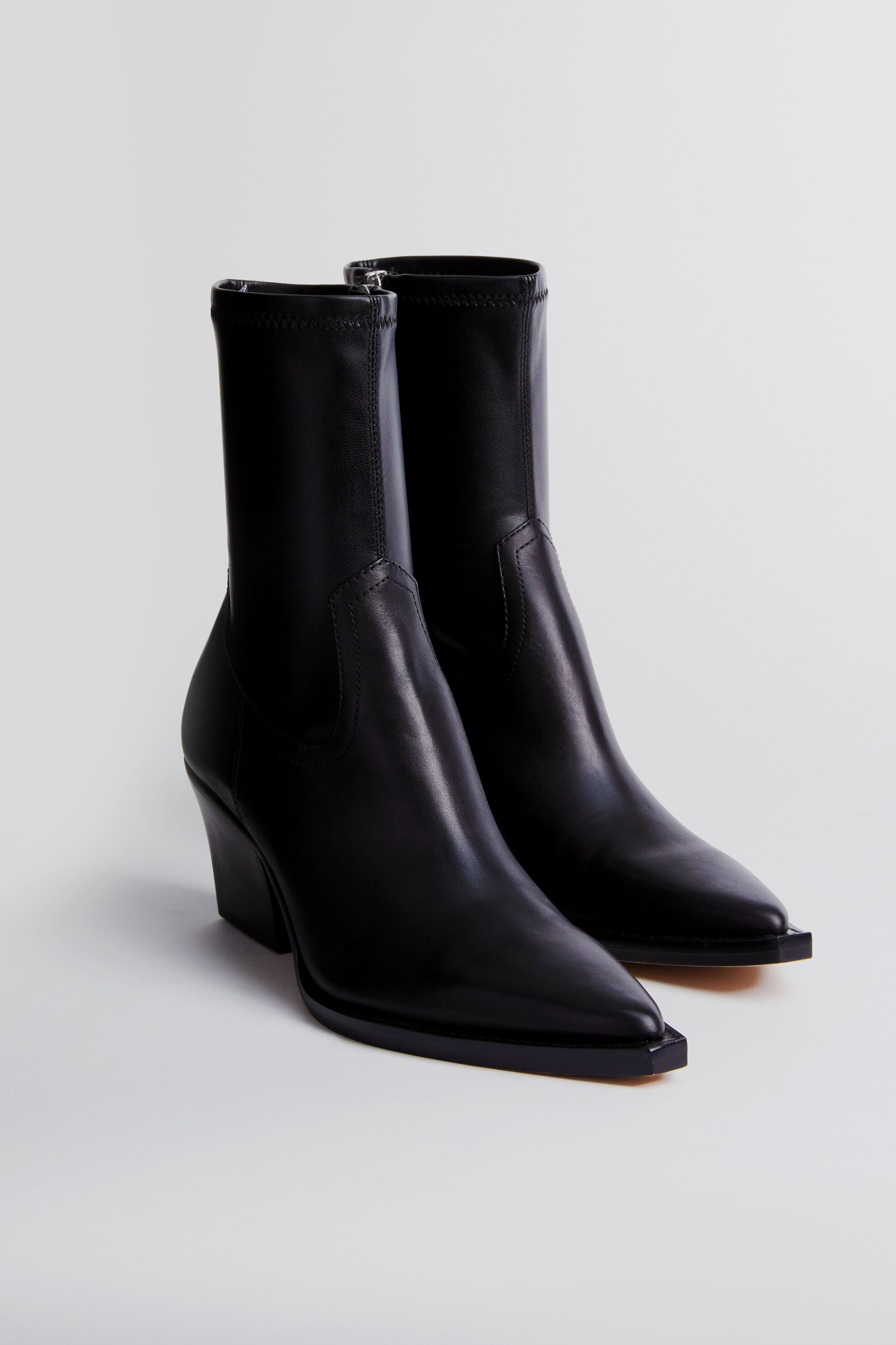 A pair of black Dolce Vita Rutger booties featuring a pointed toe and chunky heel, crafted from premium leather.