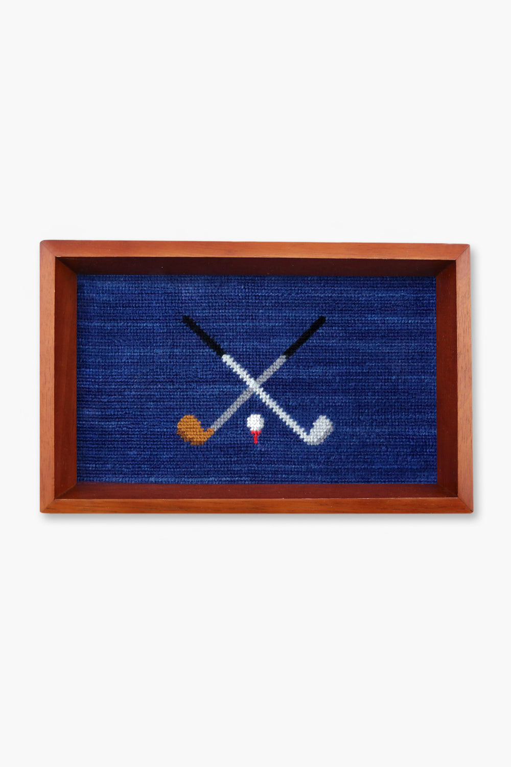 Smathers and Branson’s rectangular valet tray features a wooden frame and a needlepoint design of two crossed golf clubs above a white golf tee with a red stripe.